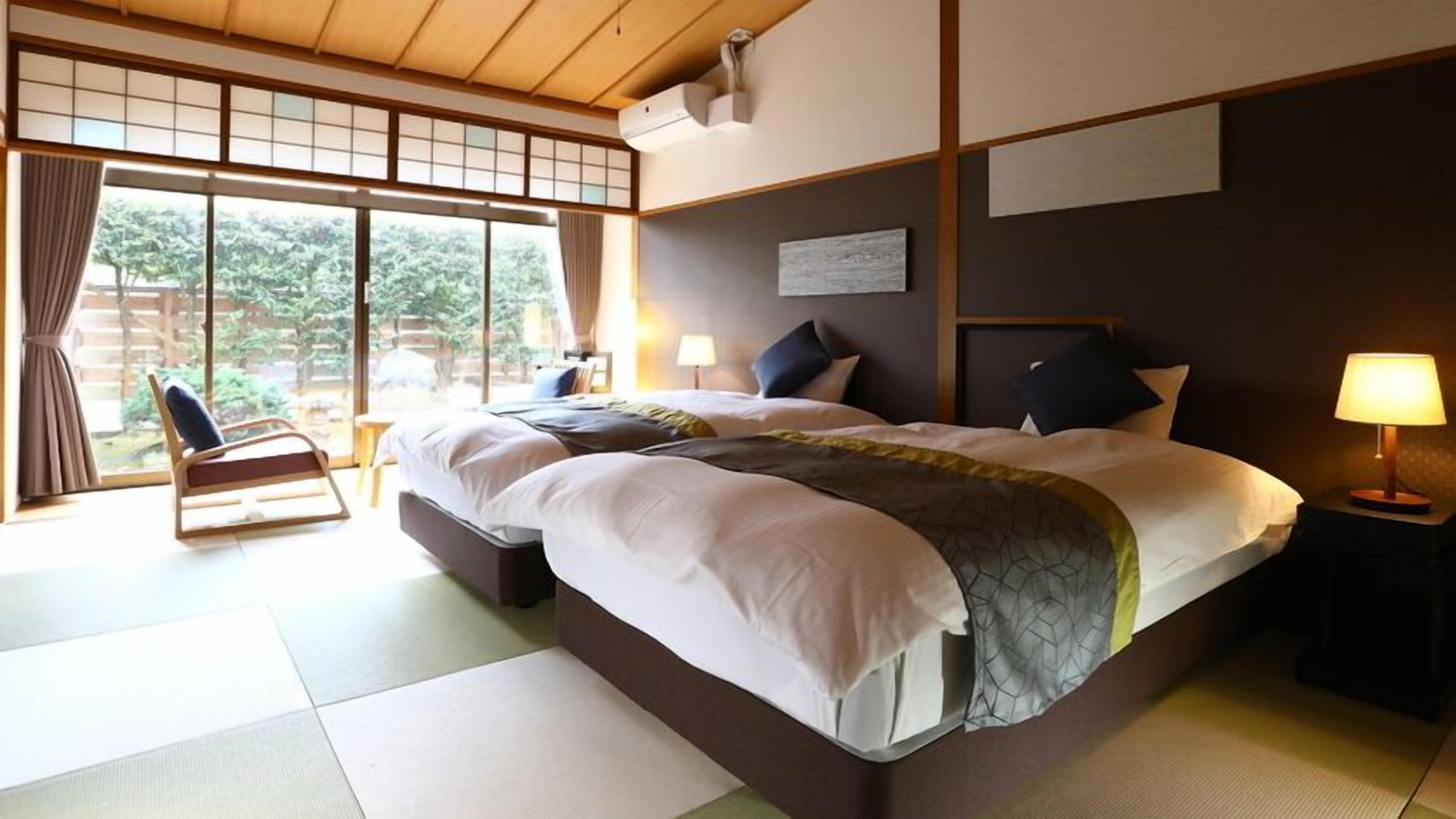 Een hotelkamer met een groot bed, een stoel, een bureau en uitzicht op groen.