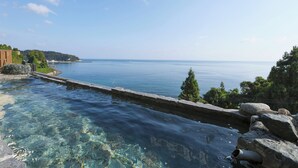 Una piscina cristalina con vista al mar y un paisaje rocoso.