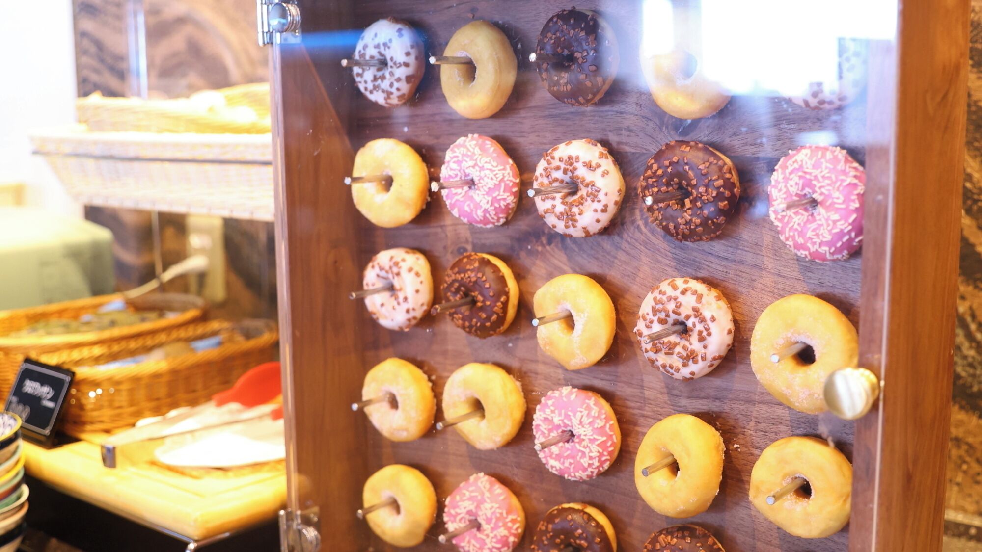 A display case with various donuts arranged in rows.