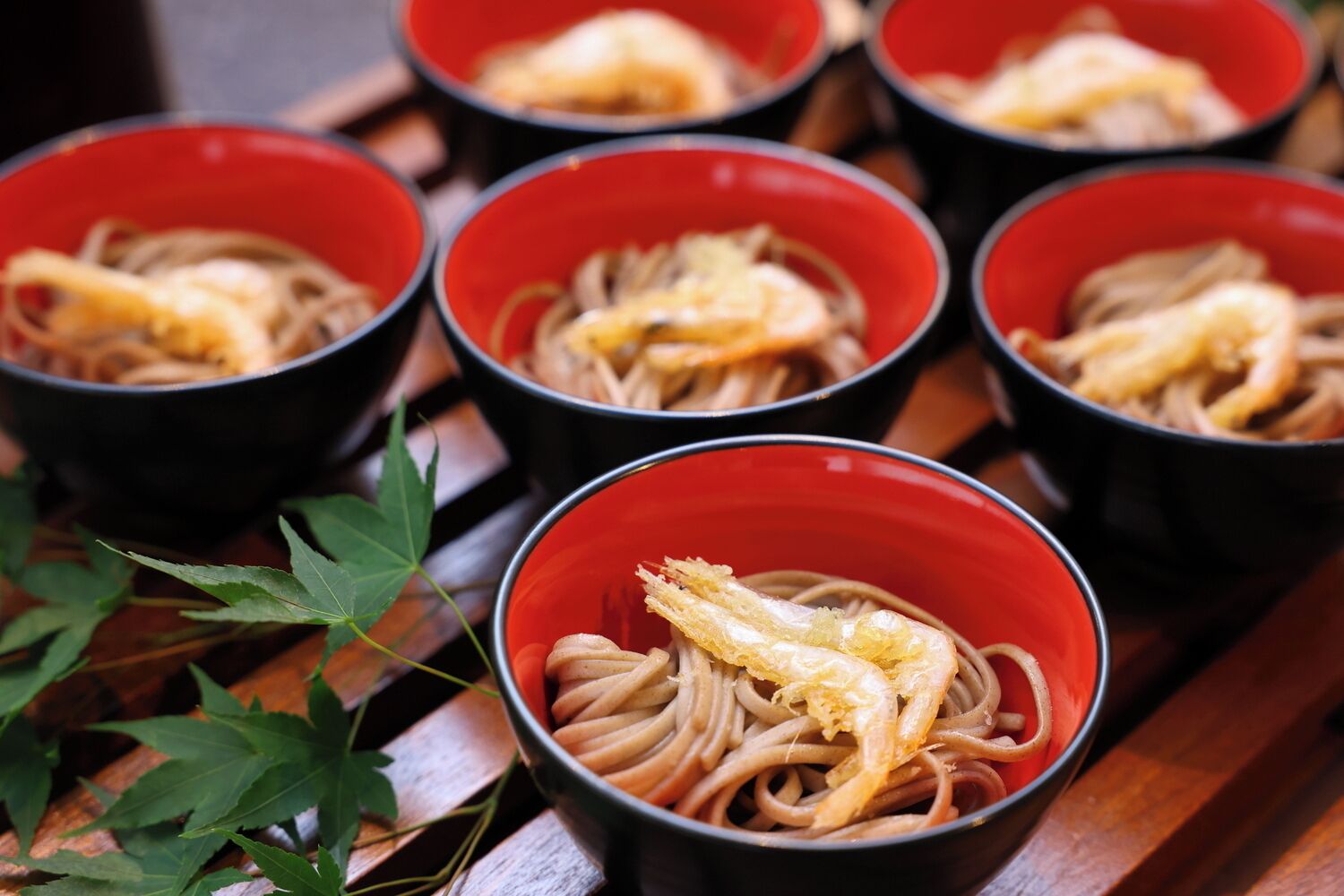 Bowls of noodles with a topping, placed on a wooden surface.
