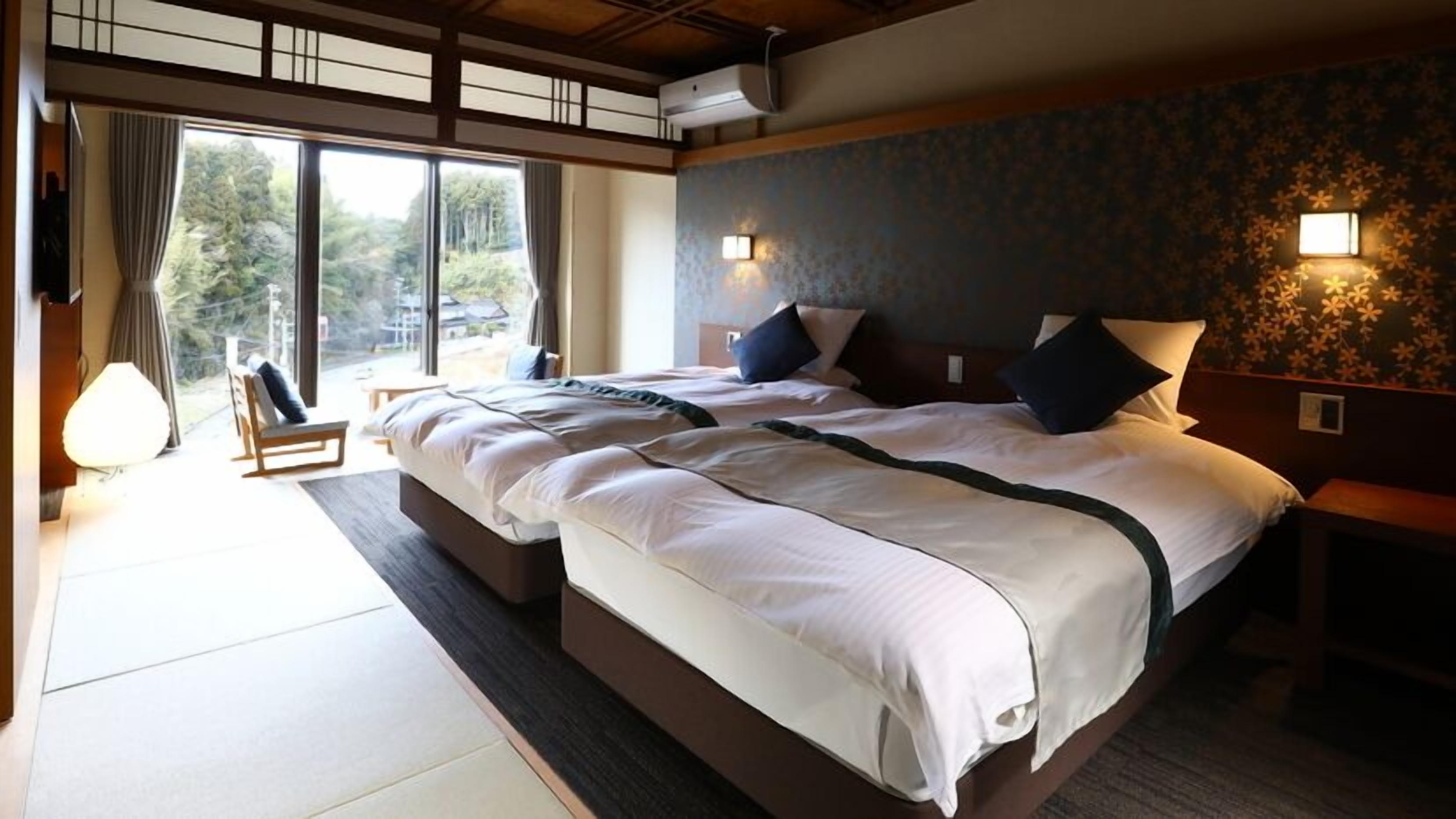 Een hotelkamer met een groot bed, twee nachtkastjes, een raam met gordijnen en uitzicht op de omgeving.