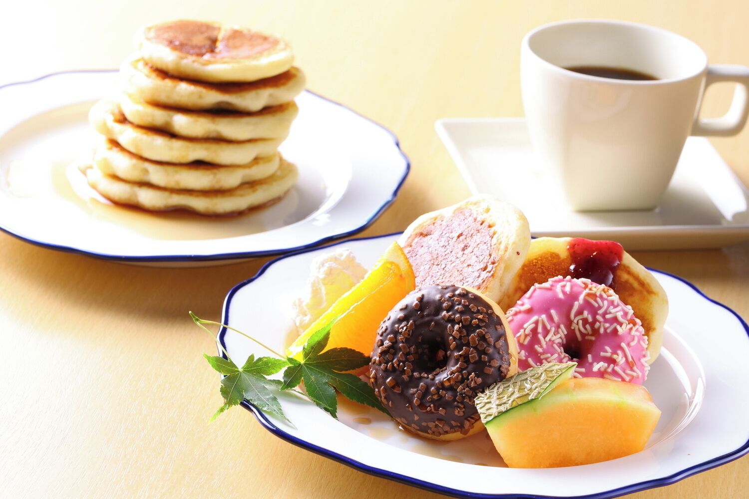 A breakfast setting with pancakes, a cup of coffee, and assorted pastries.