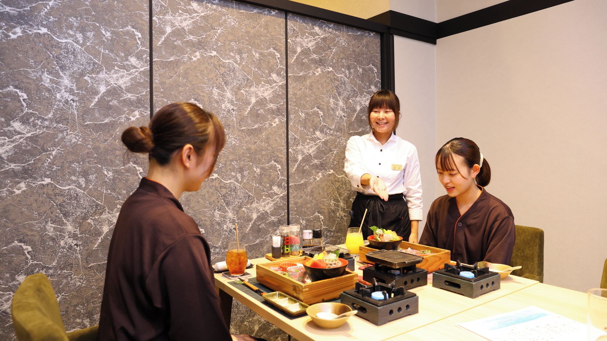 A dining area with a marble wall, a table with food, and a person serving.