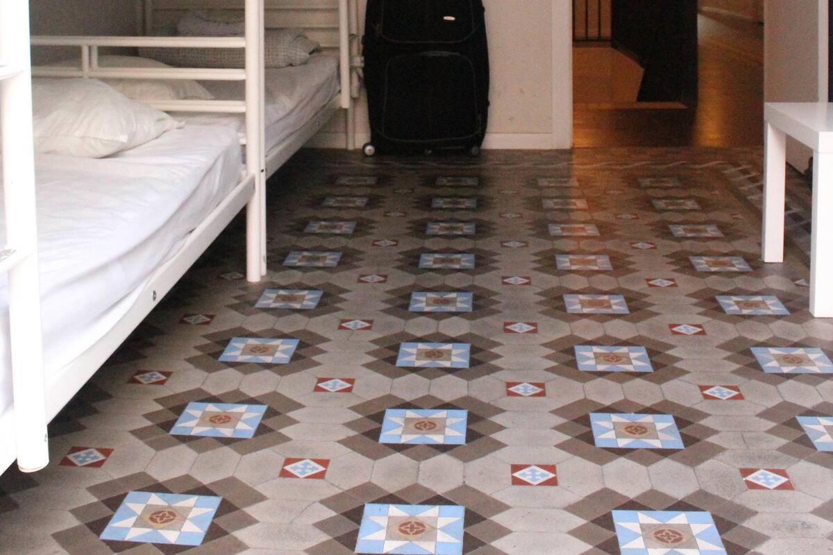A room with bunk beds, a suitcase, and a patterned floor.