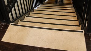 Una escalera con barandillas negras y escalones color beige.