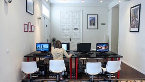 Un salón de conferencias con una puerta blanca, dos monitores y tres sillas blancas.