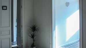 Un pasillo con piso estampado, una planta en maceta y una puerta que da a otra habitación.