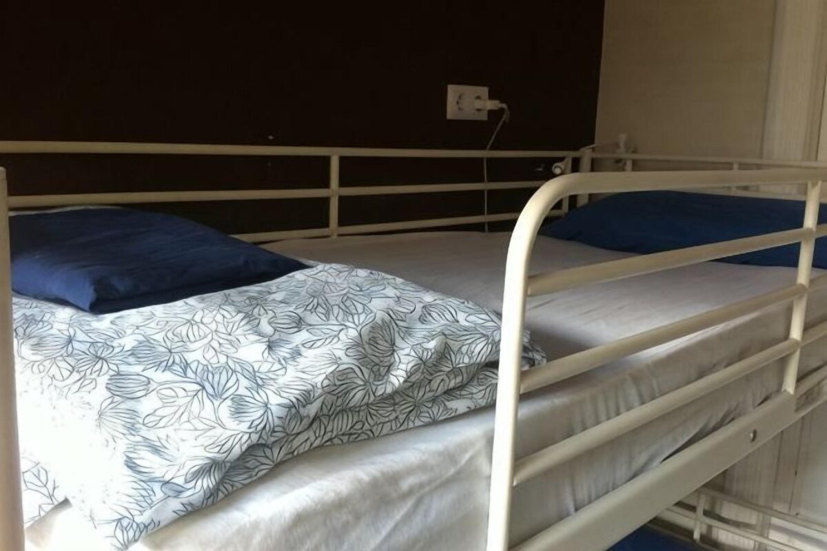 A bunk bed with a patterned bedspread and blue pillows.