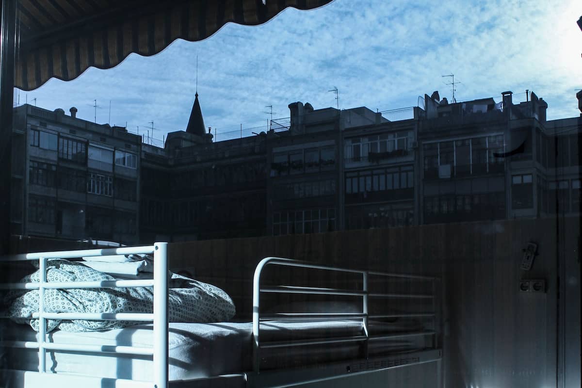 A bunk bed room with a view of buildings and a clear sky.