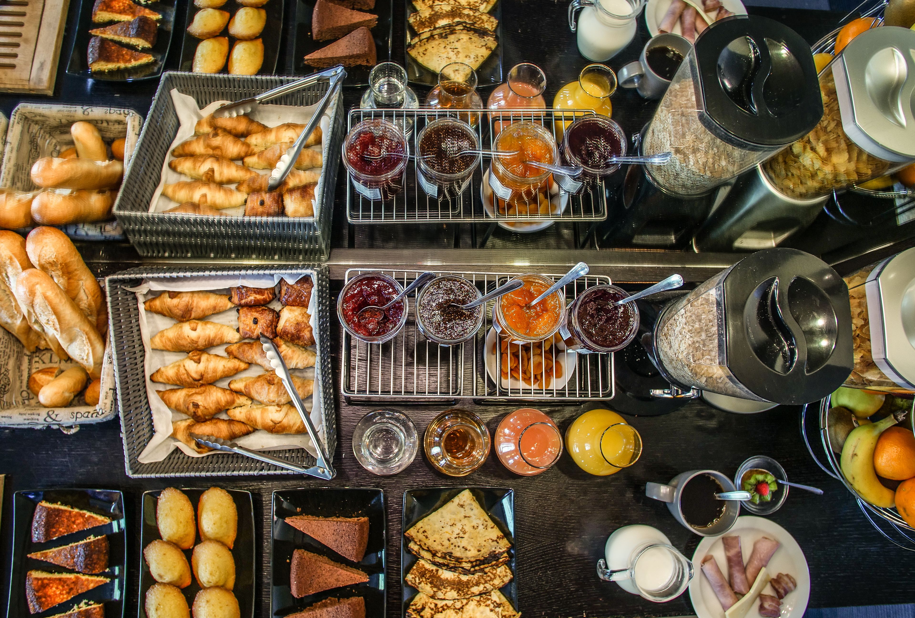 A breakfast buffet with various pastries, jams, and beverages.