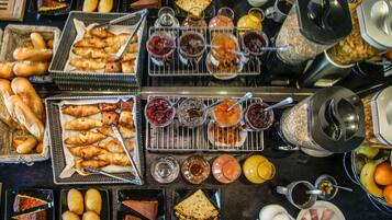 A breakfast buffet with various pastries, jams, and beverages.