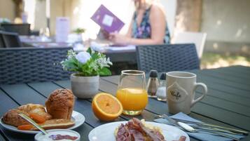 Desayuno con cruasanes, jugo de naranja y tocino sobre una mesa.