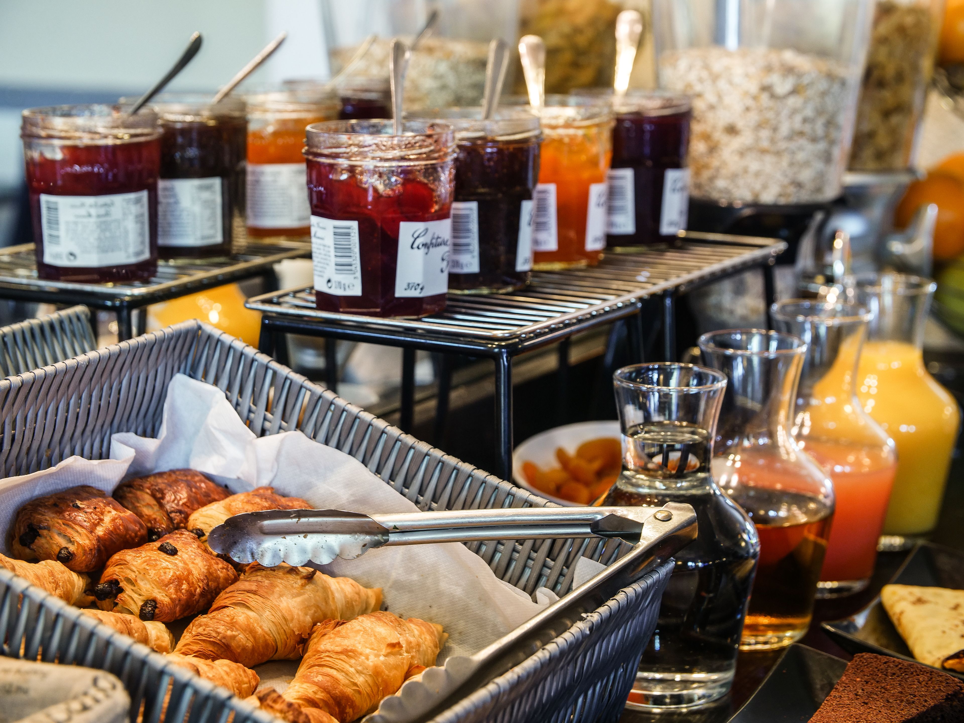 Un bufé de desayuno con pasteles, mermeladas y jugos.