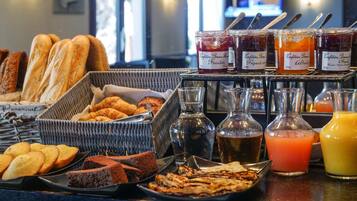 A breakfast buffet with various breads, pastries, and jams.
