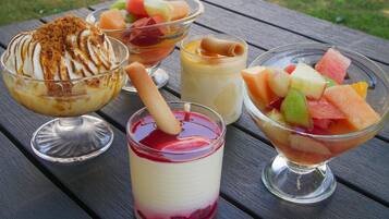 A variety of desserts on a wooden table outdoors.