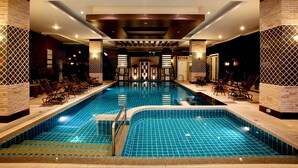 A large indoor swimming pool with a tiled floor and walls, surrounded by lounge chairs and a reception area with a check-in counter. - KTK Pattaya Hotel and Residence (Pattaya)