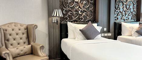 A hotel room with a tufted armchair, a bed with white linens, and decorative wall panels.