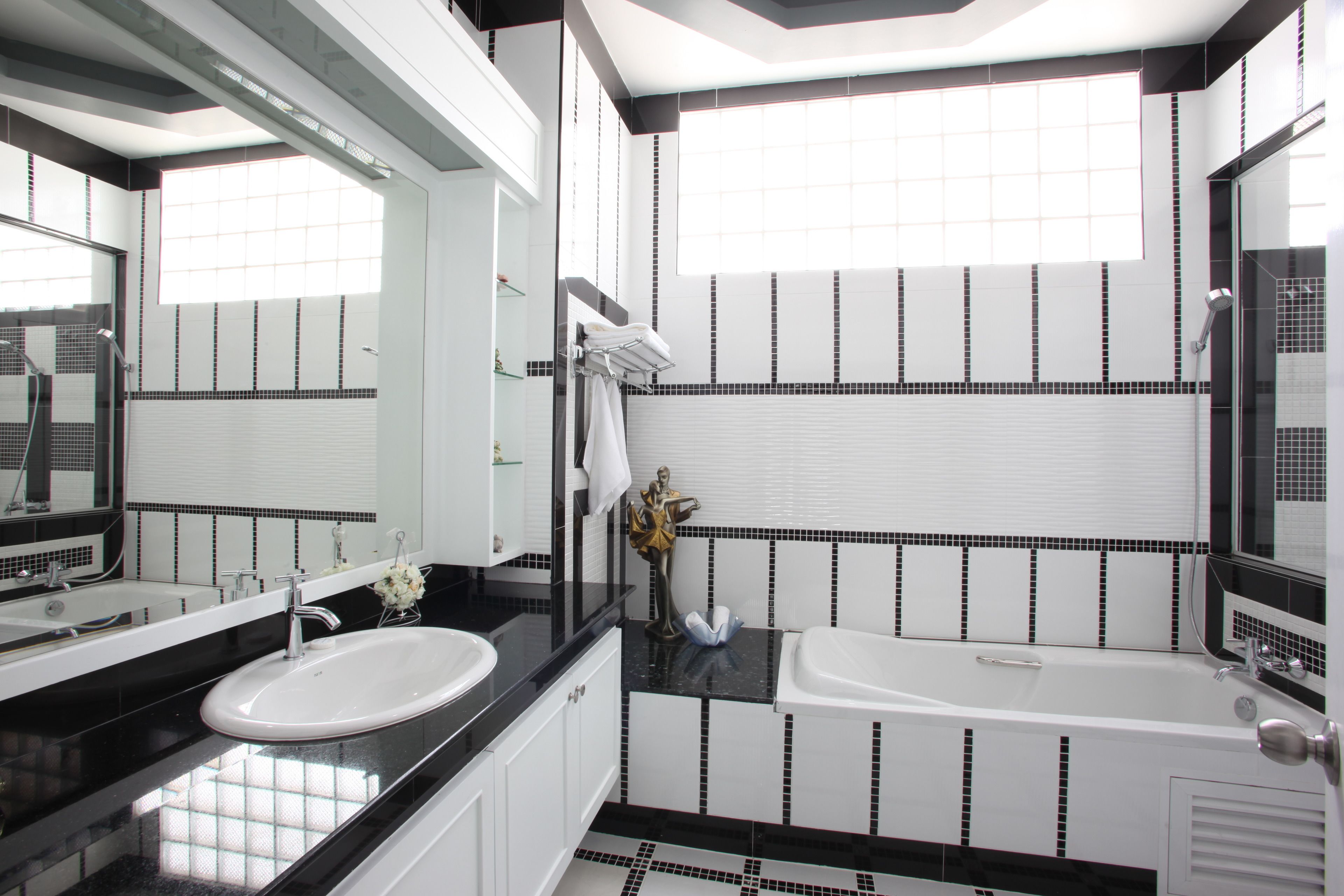 A modern bathroom with a white sink, black countertop, and a bathtub.