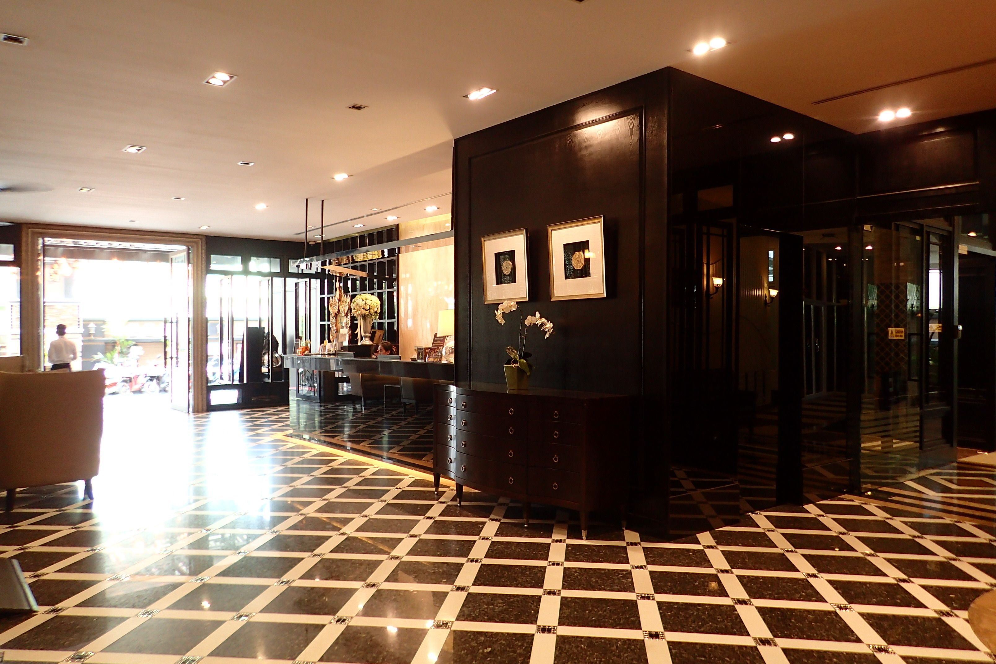 A lobby with a checkered floor, a reception desk, and framed pictures on the wall.