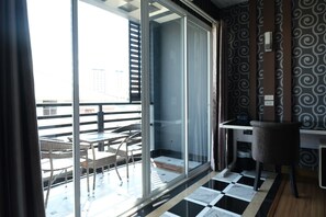 A modern room with a large sliding glass door leading to an outdoor balcony, a small desk, and a chair. - KTK Pattaya Hotel and Residence (Pattaya)