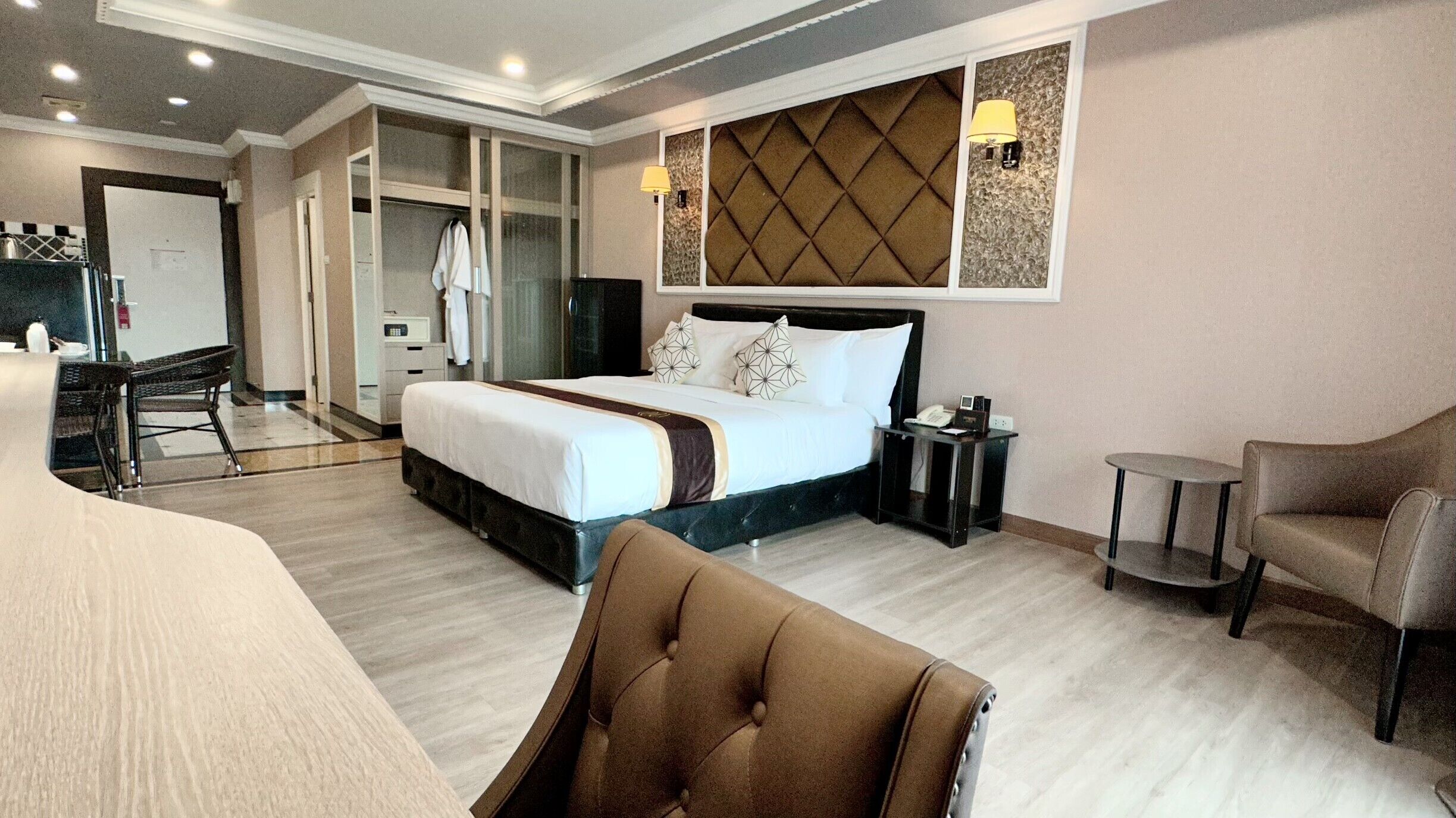 A hotel room with a bed, a desk, a chair, and a small table.