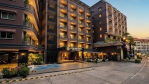 A multi-story hotel with a modern design, featuring balconies, a well-lit entrance, and a parking area. - KTK Pattaya Hotel and Residence (Pattaya)