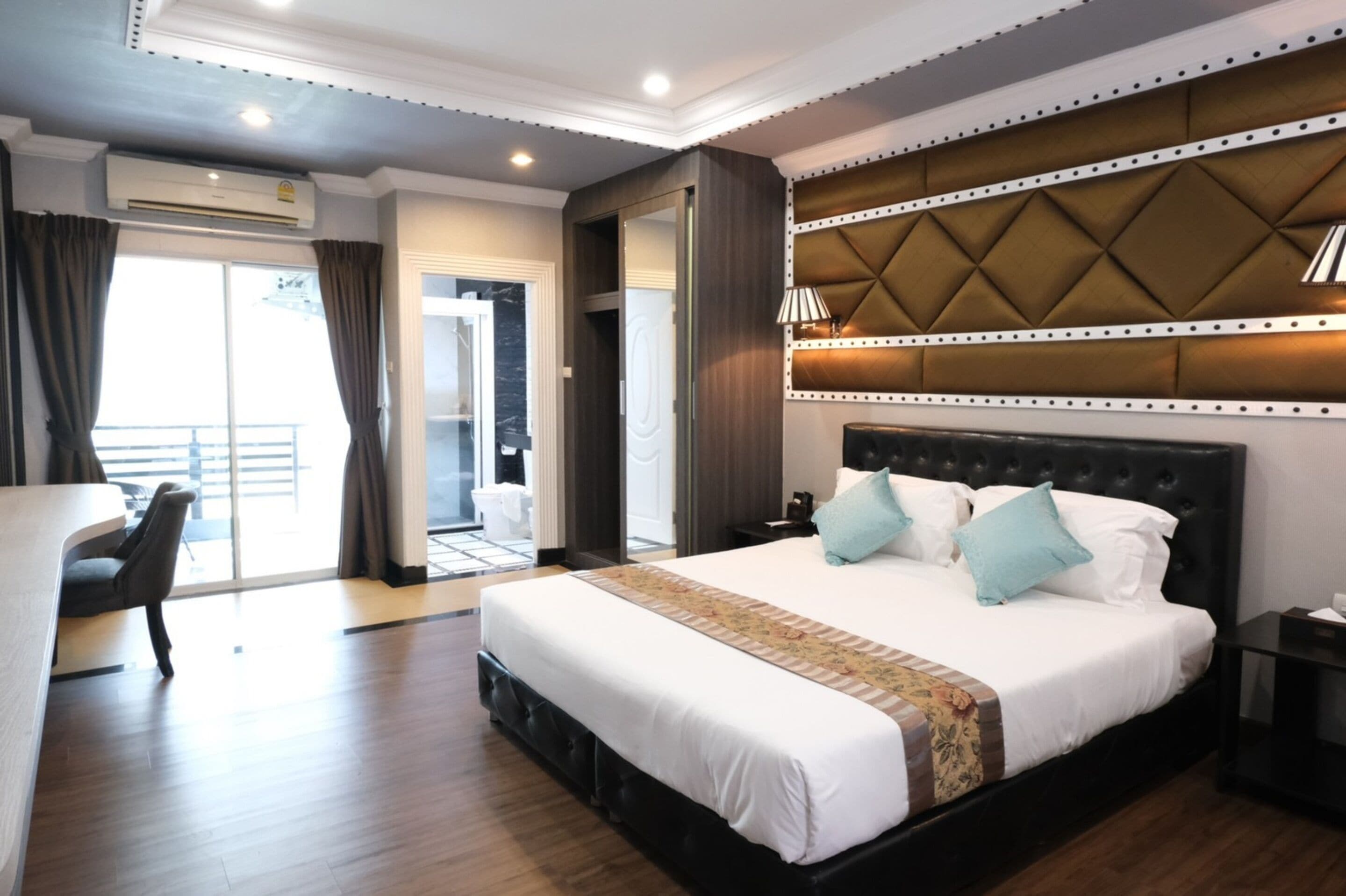 A hotel room with a large bed, a desk, and a view of the outside.