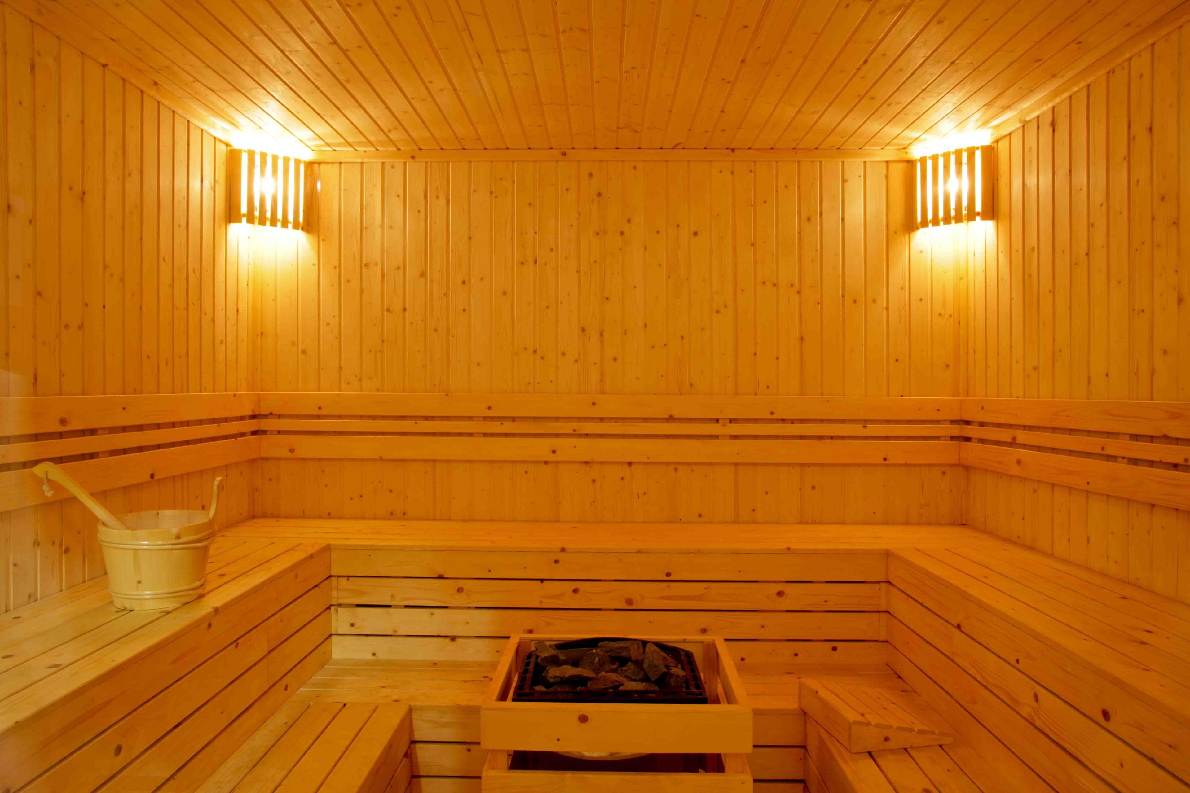 A wooden sauna with benches, a bucket, and a grate for burning wood.