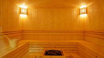 A wooden sauna with benches, a bucket, and a grate for burning wood.