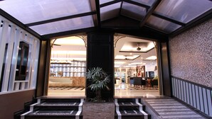 A hotel lobby with a central staircase, a potted plant, and a view into the dining area. - KTK Pattaya Hotel and Residence (Pattaya)