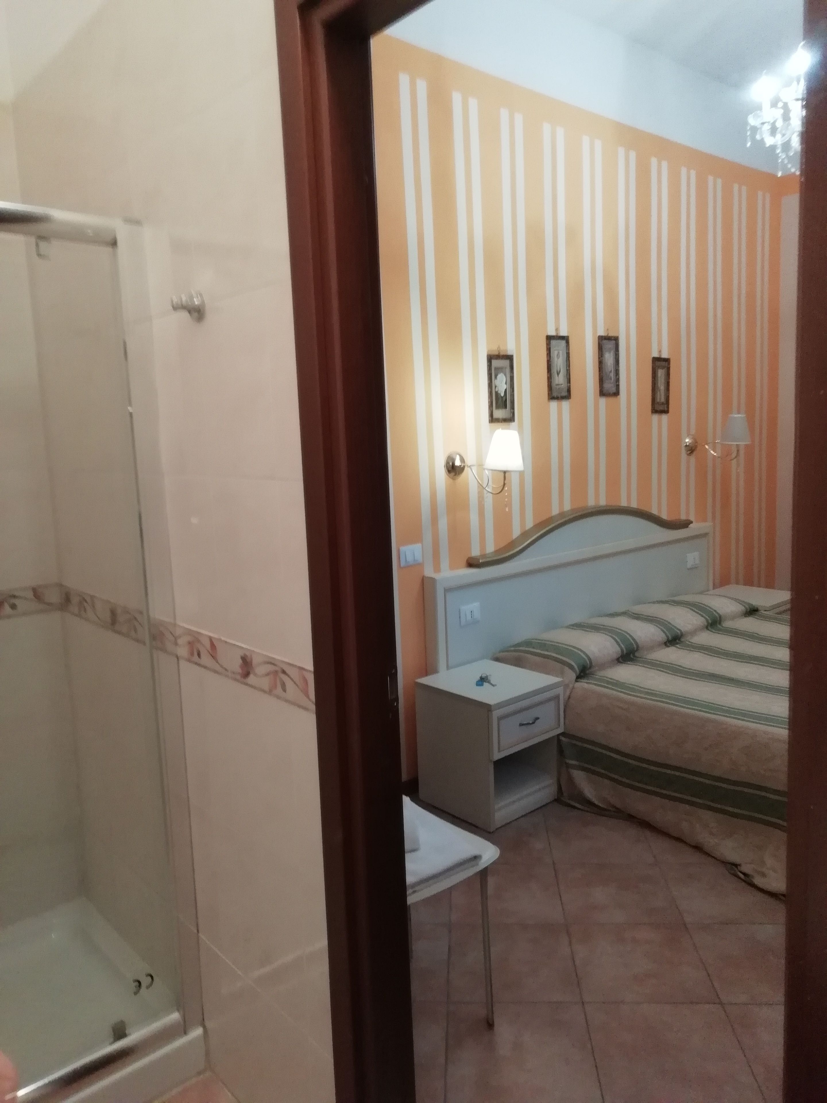 Une chambre à coucher comprenant un lit, une table de chevet et un espace douche.