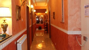 A hotel hallway with a radiator, wall-mounted lamps, and a telephone.
