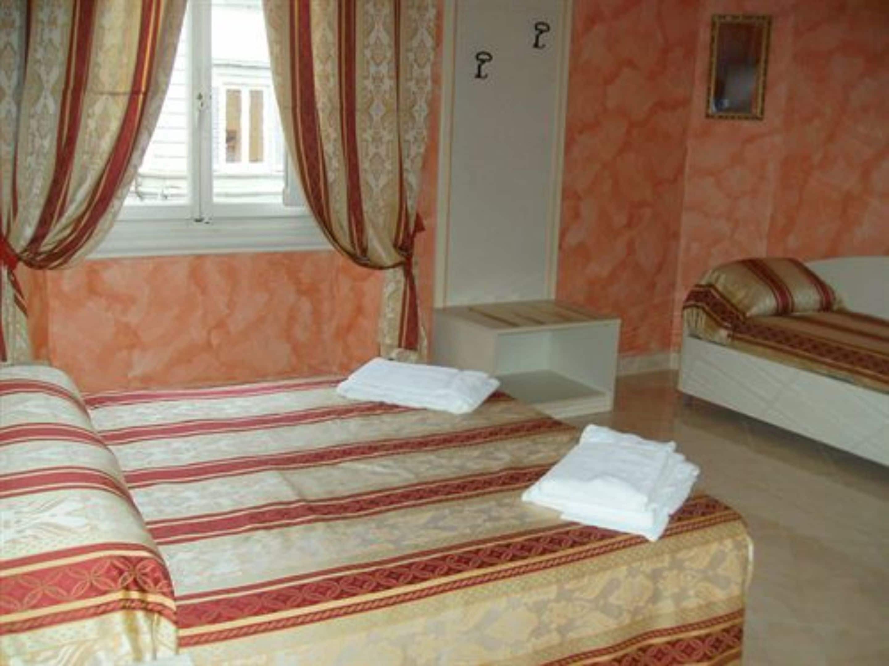 Une chambre d’hôtel avec deux lits, une petite table de chevet, un canapé et une fenêtre avec des rideaux.