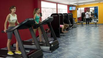 Un gimnasio con cintas de correr, pesas y una pantalla de televisión.