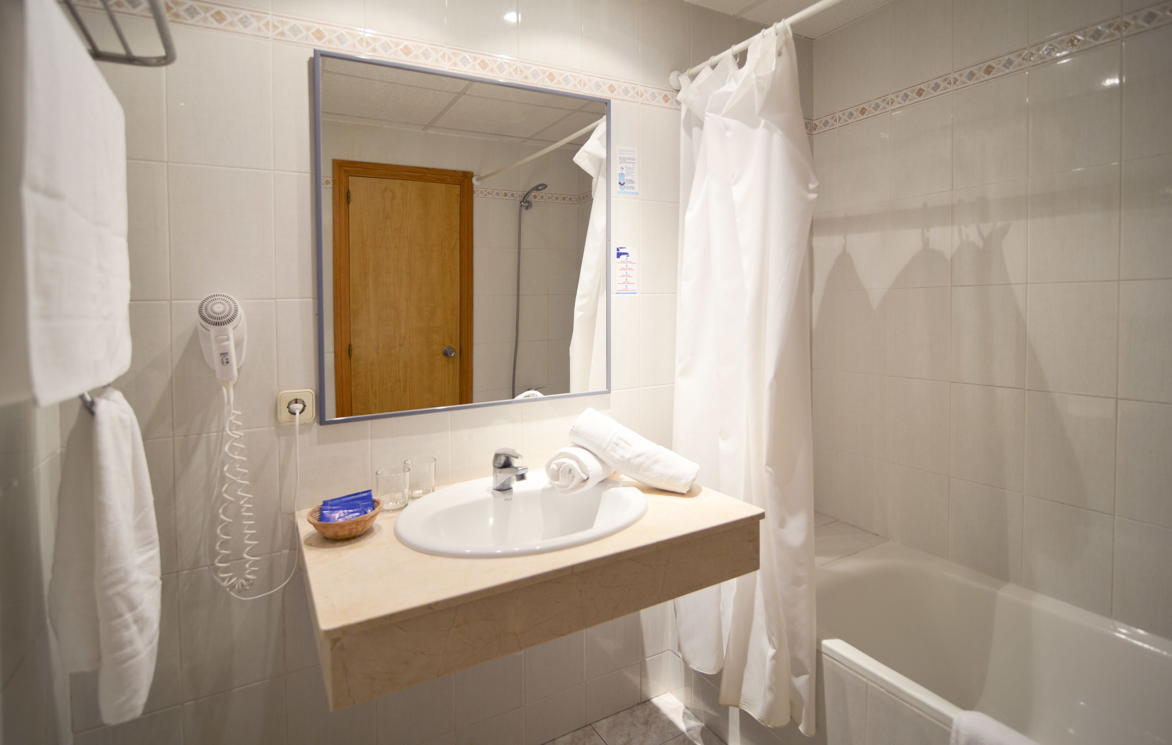 A bathroom with a sink, mirror, shower, and a towel rack.