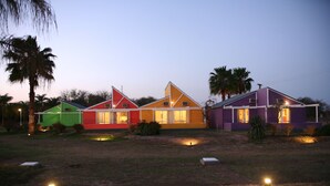 A row of colorful houses with a swimming pool in the foreground. - Cabañas Marina House (Termas de Rio Hondo)