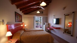 A hotel room with two beds, a television, a red nightstand, and a ceiling fan. - Cabañas Marina House (Termas de Rio Hondo)