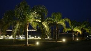 A nighttime view of a resort with palm trees and illuminated lounge chairs. - Cabañas Marina House (Termas de Rio Hondo)