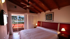 A hotel room with a large bed, a ceiling fan, a painting on the wall, and a view of the pool through the sliding door. - Cabañas Marina House (Termas de Rio Hondo)
