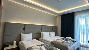 Ein Hotelzimmer mit zwei Betten, einem modernen Deckenstil und Blick auf die Stadt.