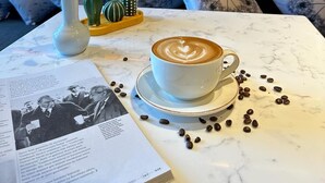 Ein gemütlicher Sitzbereich mit Tisch, dekoriert für eine Kaffeepause, einer Vase mit Trockenblumen und einem Buch.