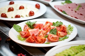 A variety of food items on plates, including sliced tomatoes and greens.