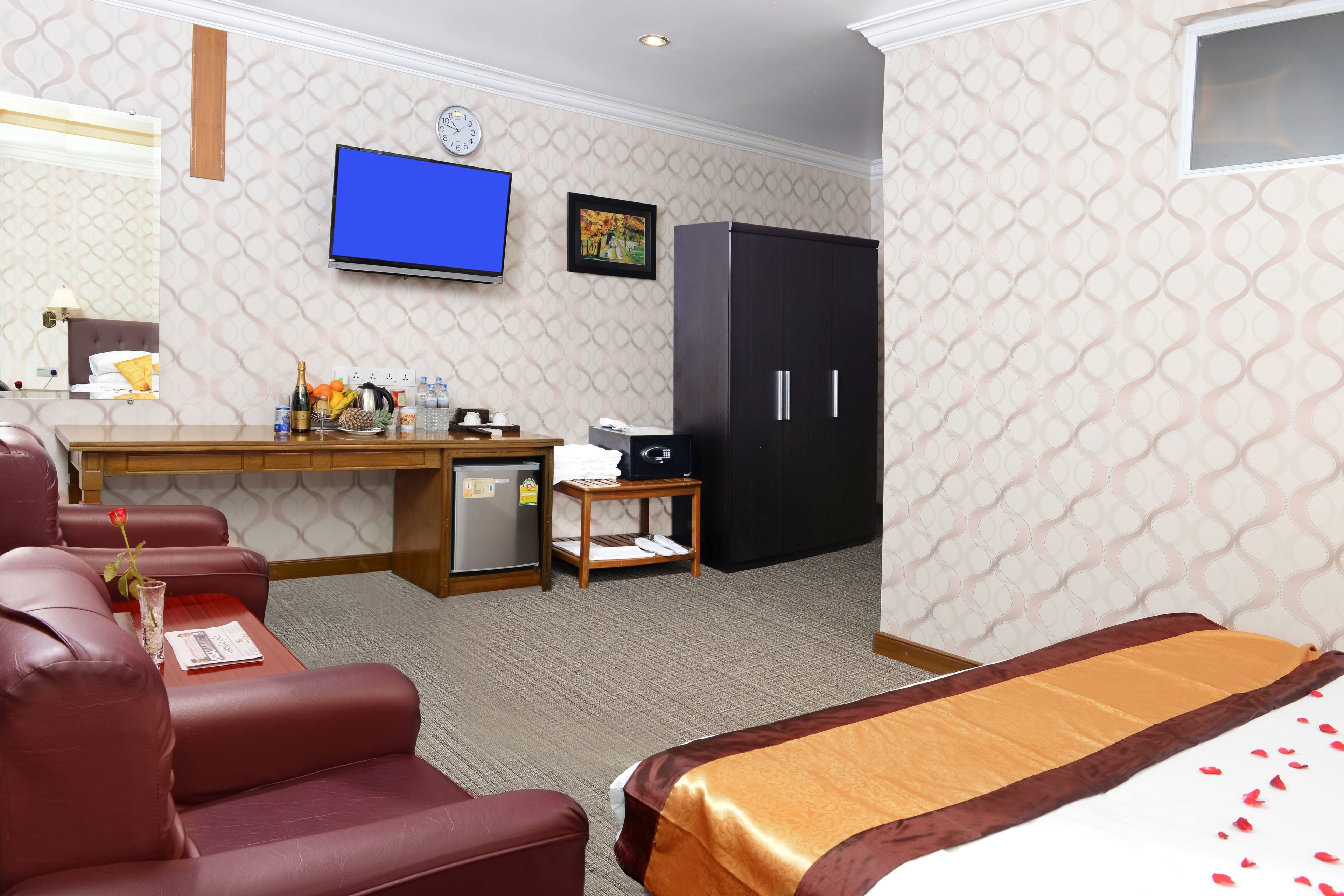 A hotel room with a bed, a desk, a TV, a wardrobe, and a seating area with a chair and a table.
