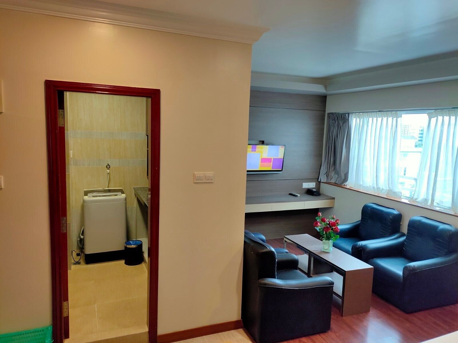 A modern living room with a flat-screen TV, two leather sofas, a coffee table, and a small table with flowers.