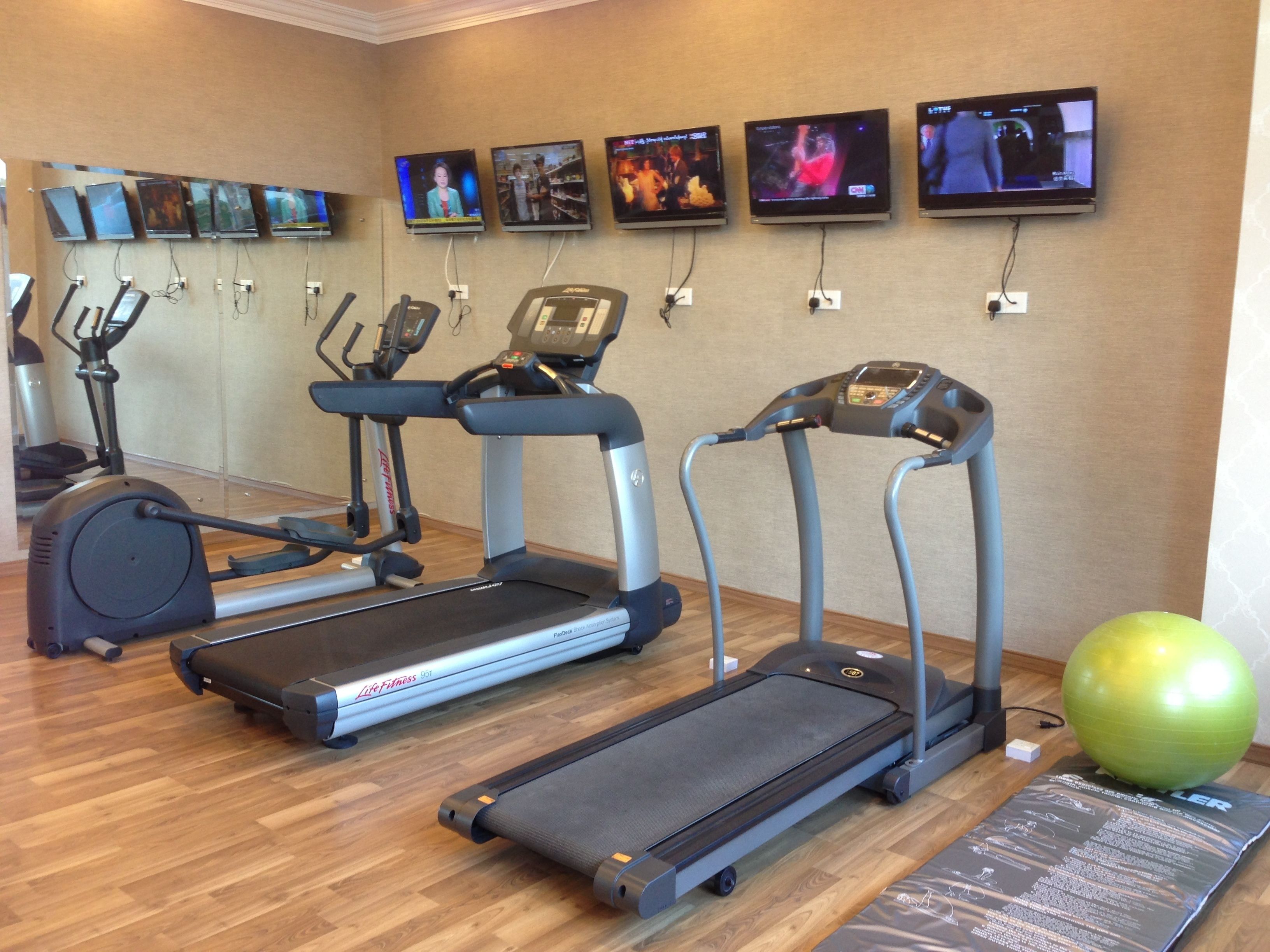Un gimnasio con cintas de correr, bicicletas estáticas y pelotas de ejercicio.