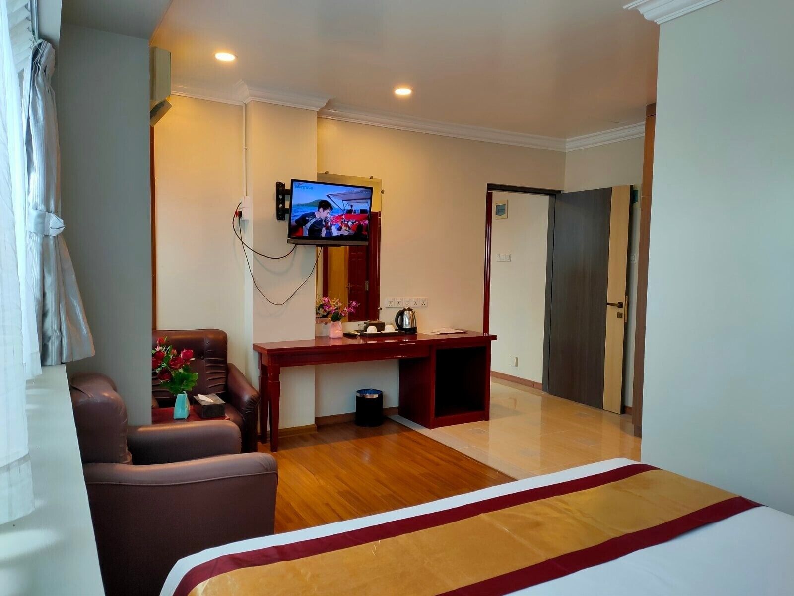 Una habitación de hotel con cama, escritorio, silla, televisor y puerta.
