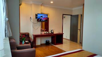 Una habitación de hotel con cama, escritorio, silla, televisor y puerta.