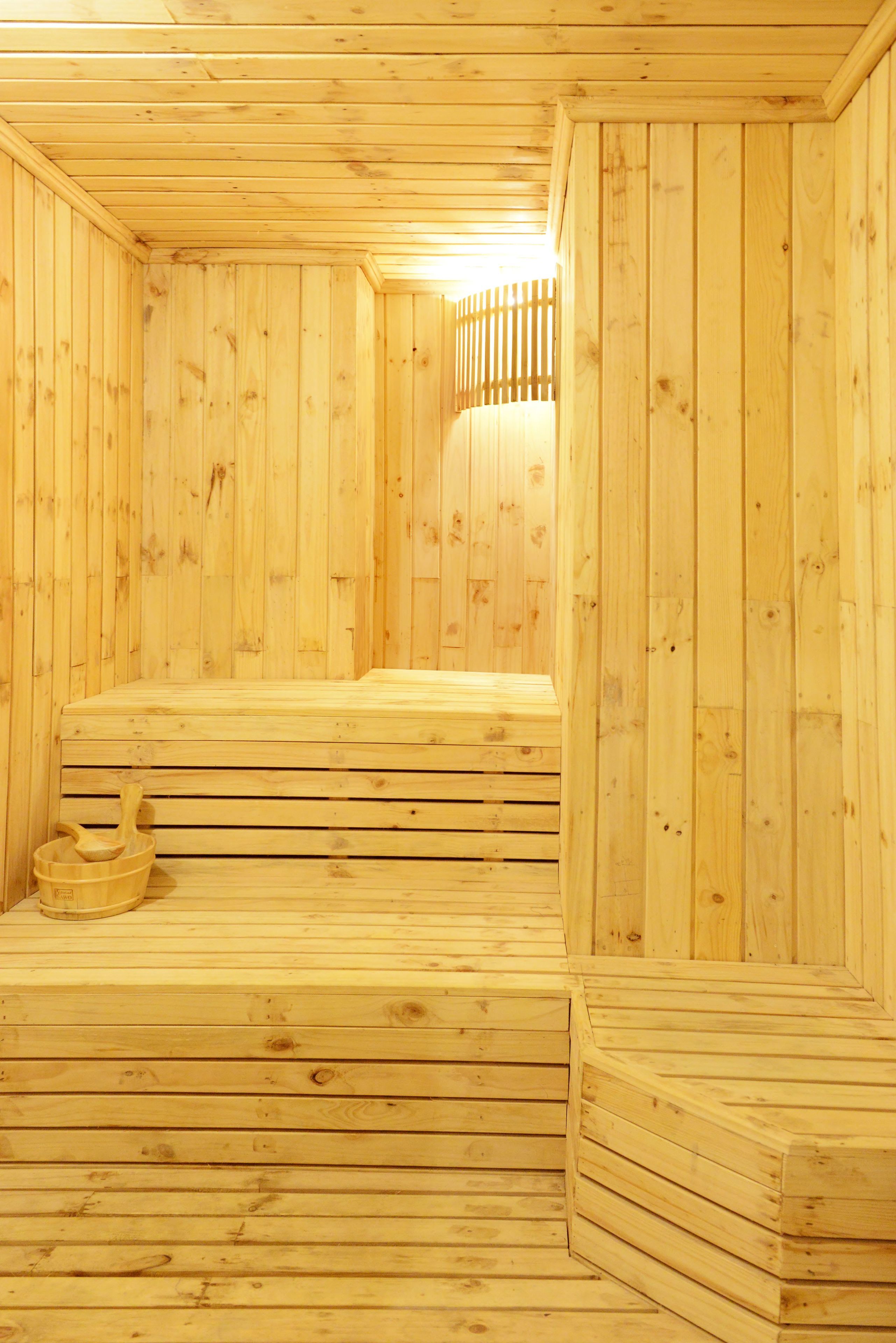 A wooden sauna with benches and a wooden bucket.