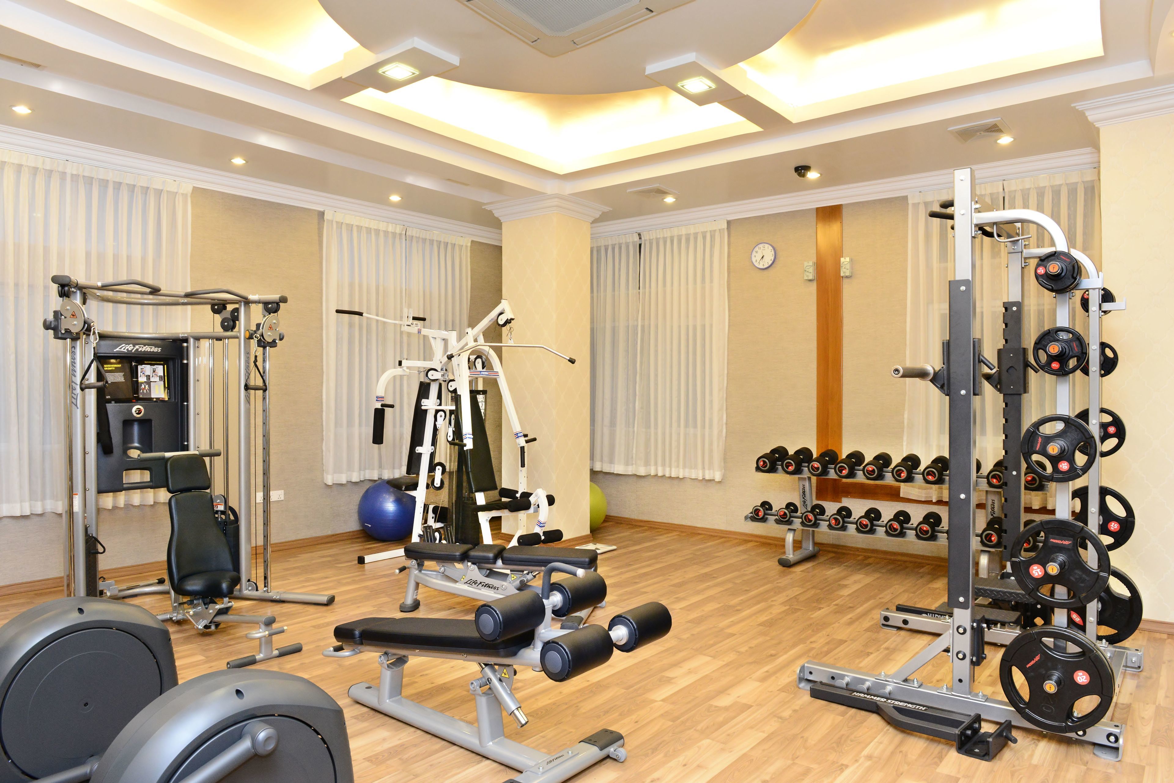 Un gimnasio con diversos equipos de ejercicio, incluyendo una prensa de banca, mancuernas y una estructura para sentadillas.