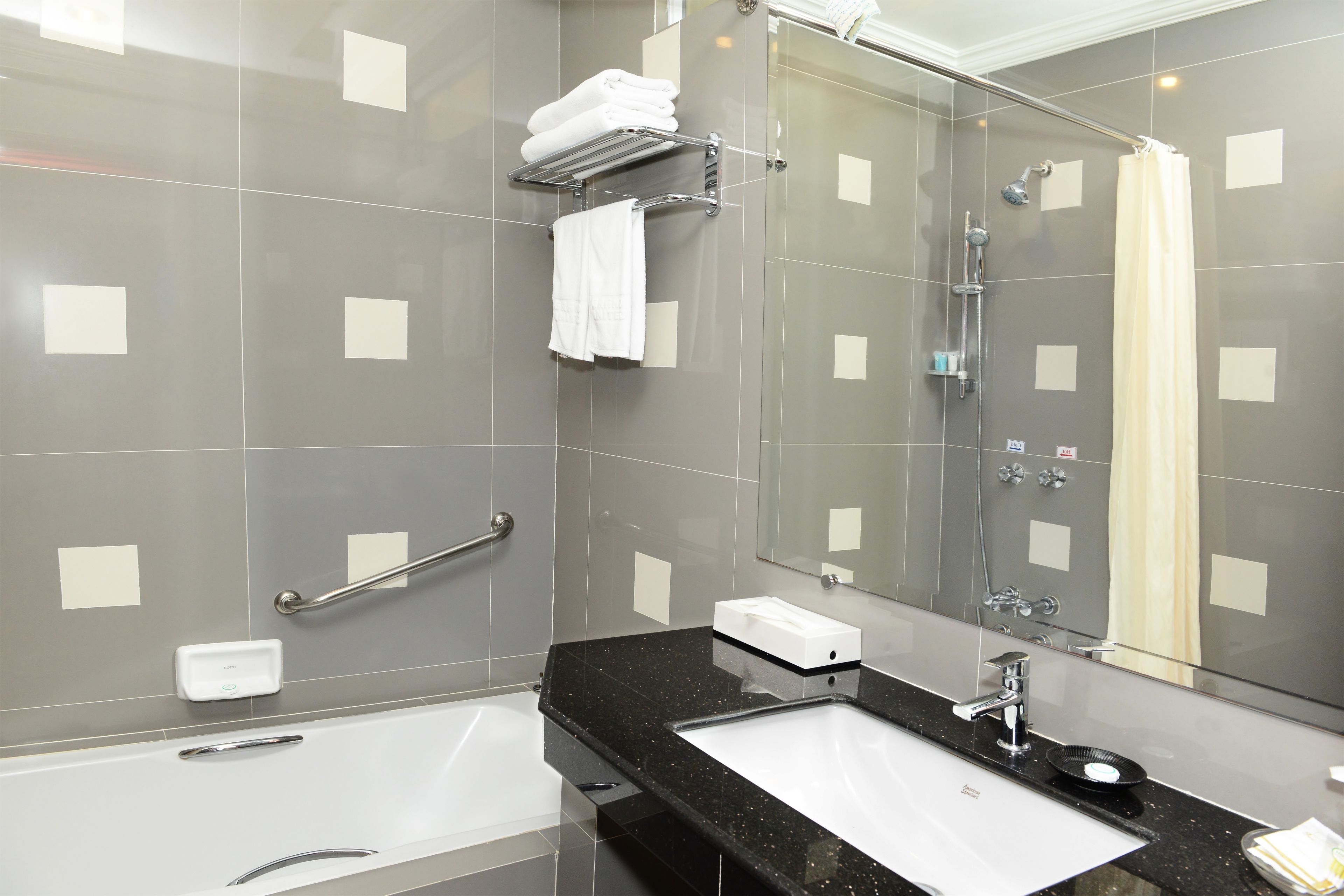 A modern bathroom with a bathtub, a sink, a mirror, and a shower area.